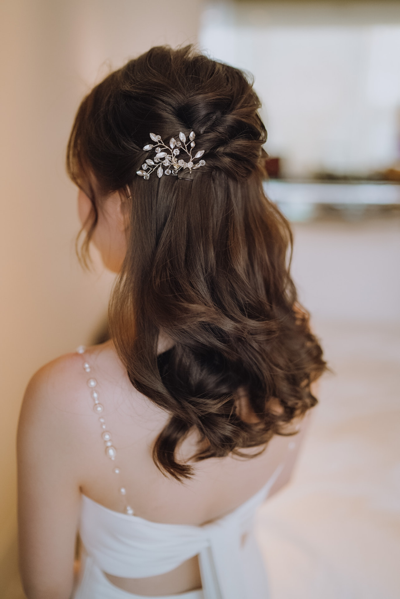 Bride's half-up twists pinned with a crystal leaf comb