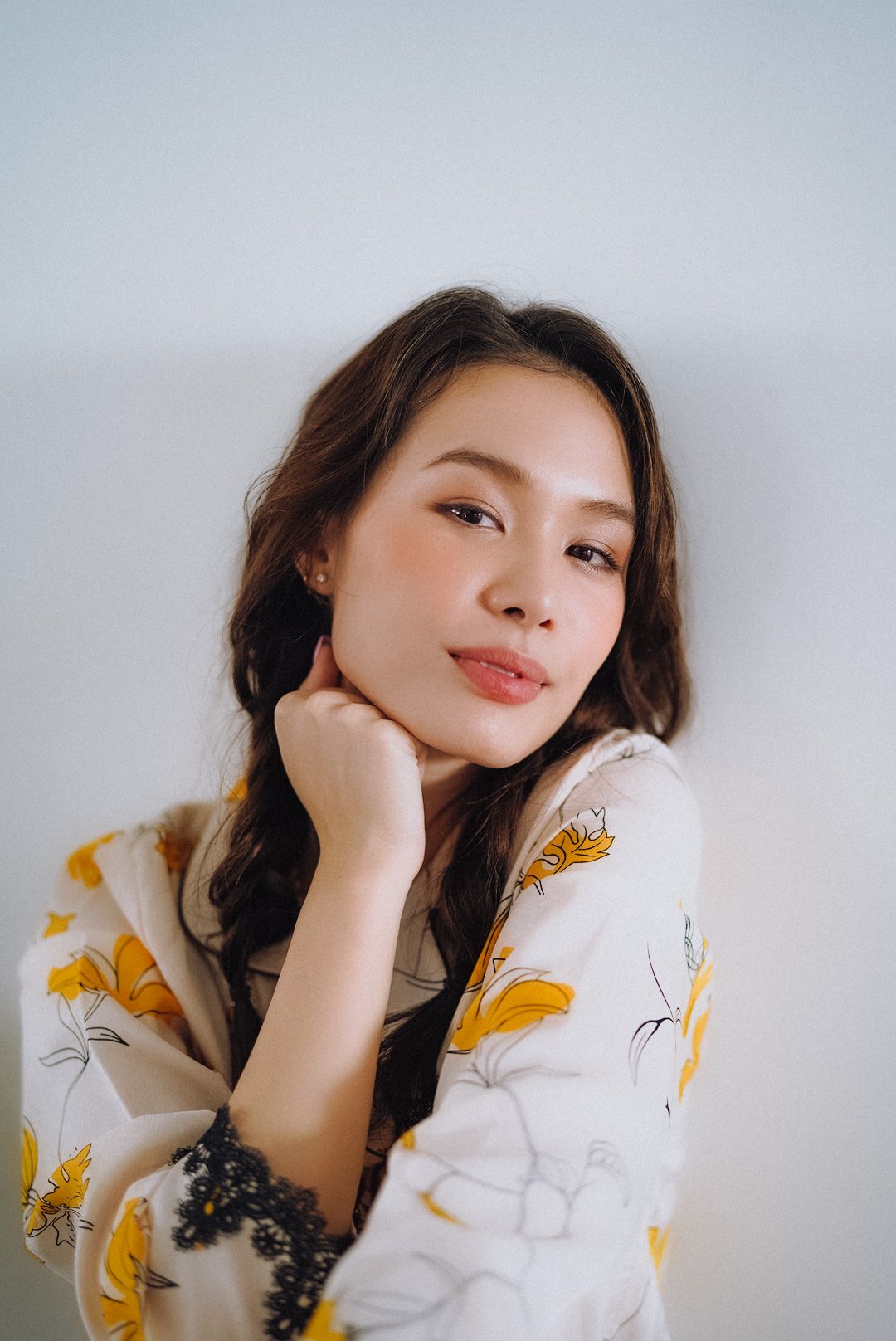 Cala Barrett — resting her chin on her hand in the yellow floral robe