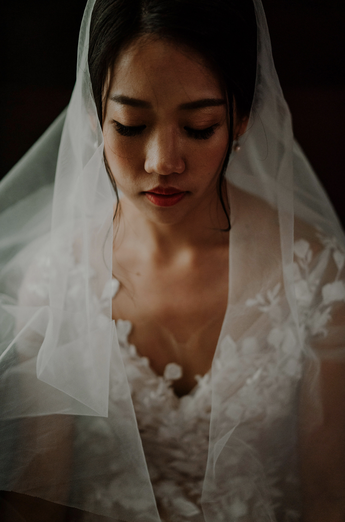 Bride in her veil and floral lace gown, eyes lowered