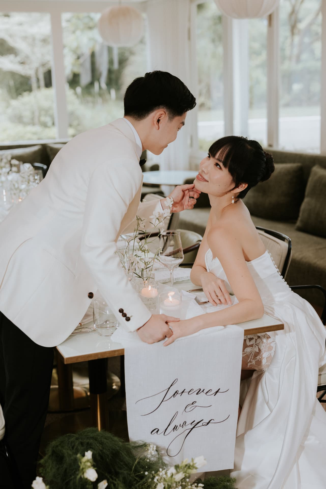 Cloud Dancer — the groom lifting the bride's chin across the table