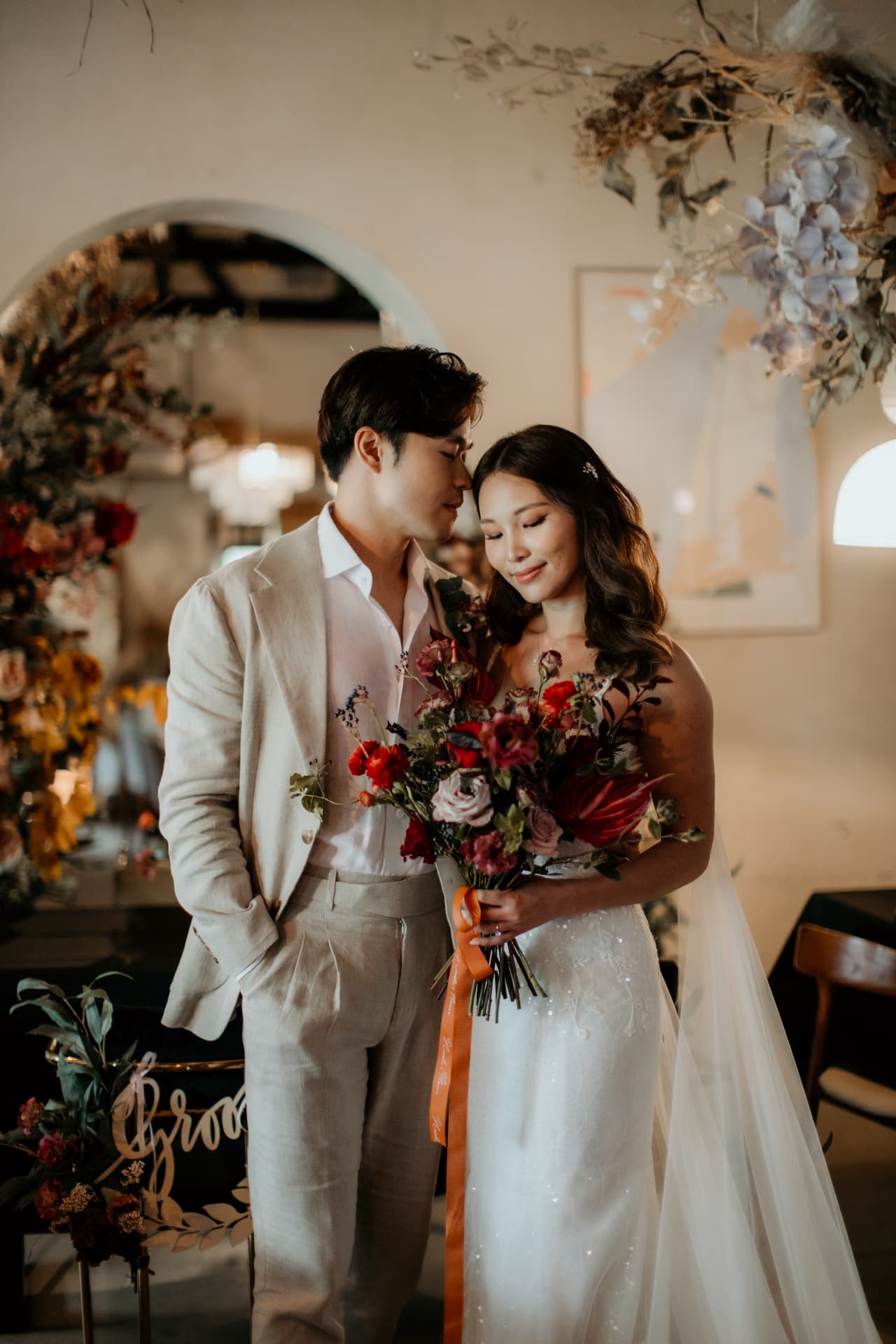 Benzo & Stacey — couple holding a rich red bouquet by the groom sign