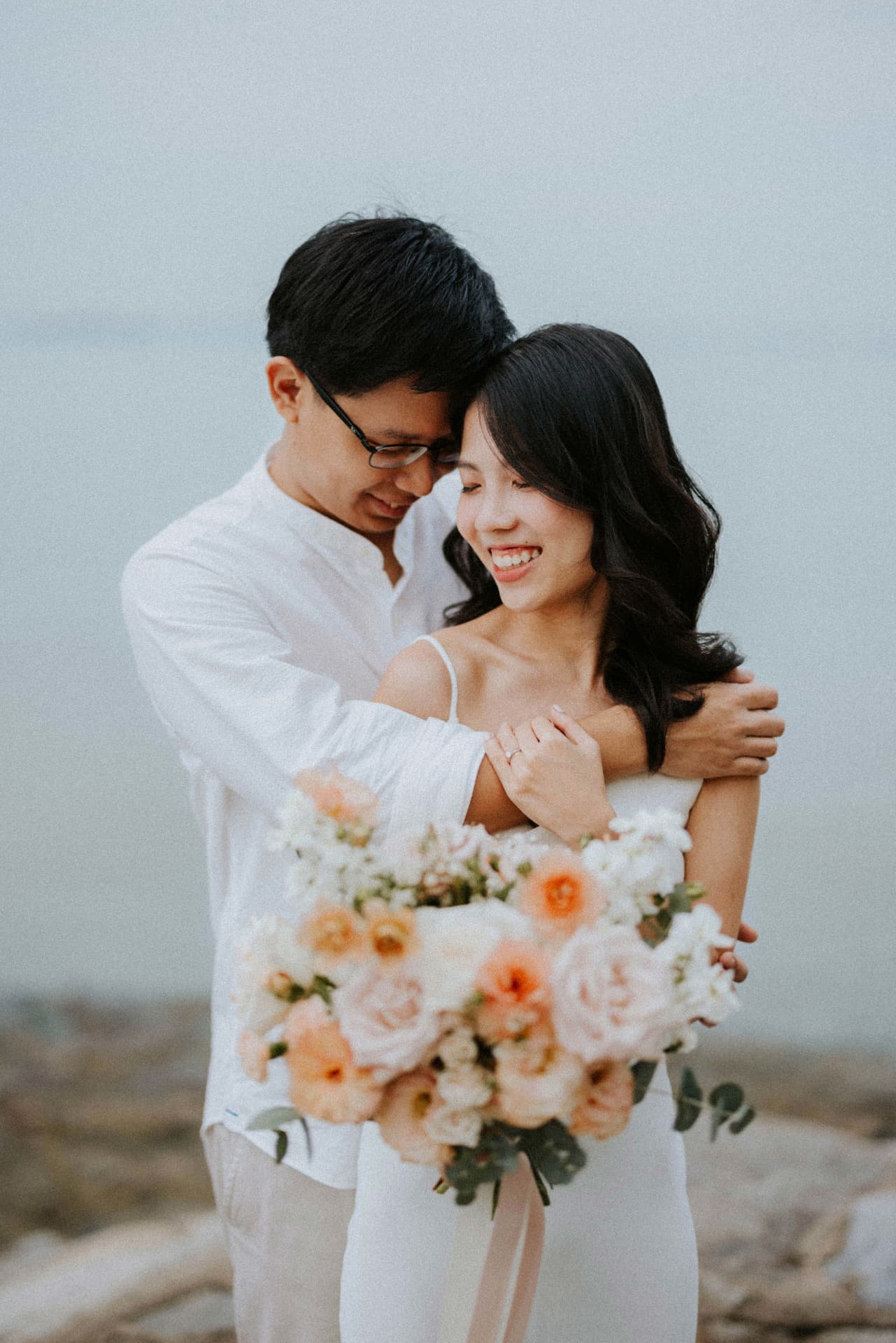 Couple beneath the veil of sea mist with their bouquet