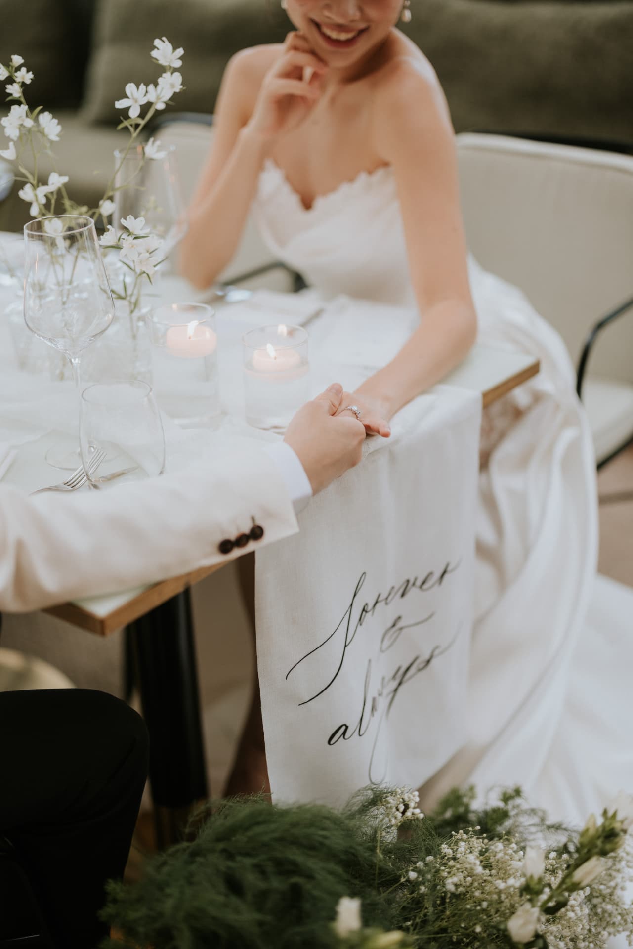 Cloud Dancer — close-up of their hands and ring beside the candles