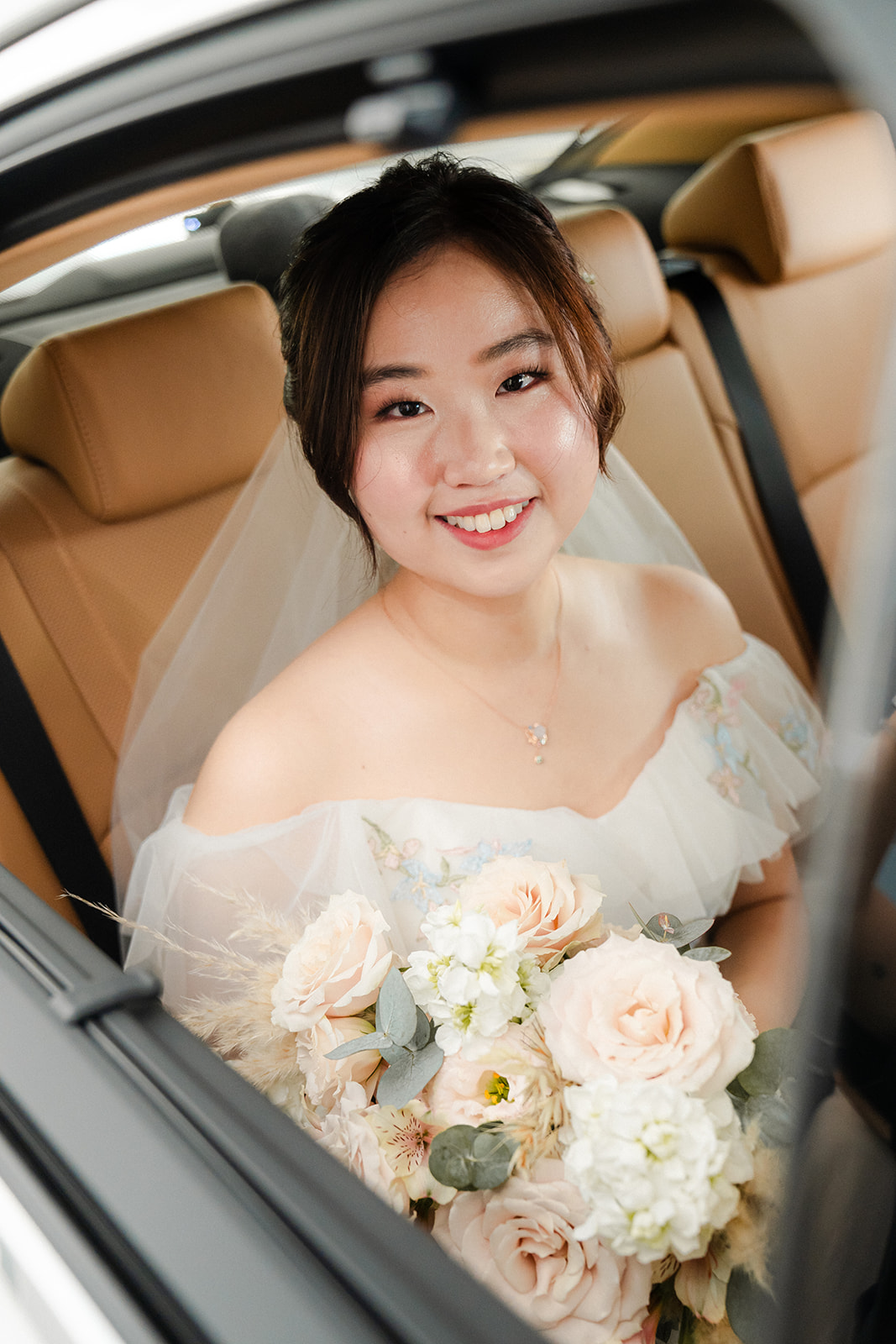 Bride in the back seat of the car with her blush bouquet