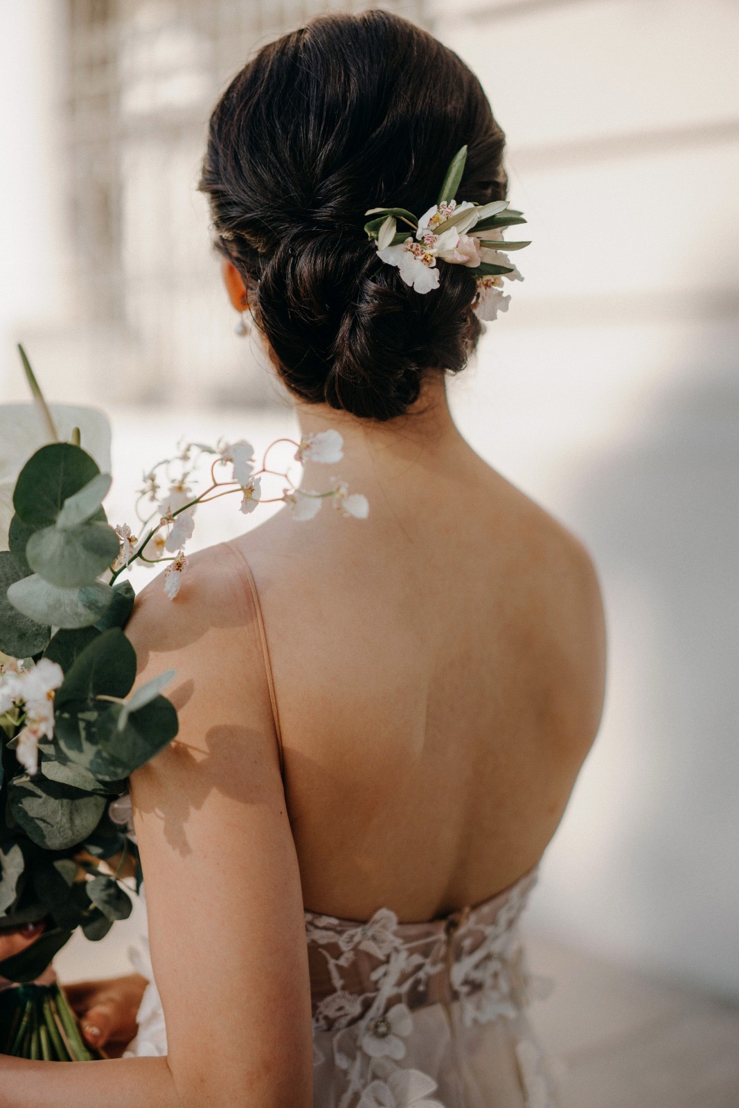 Bride — twisted low updo with orchids, holding her bouquet