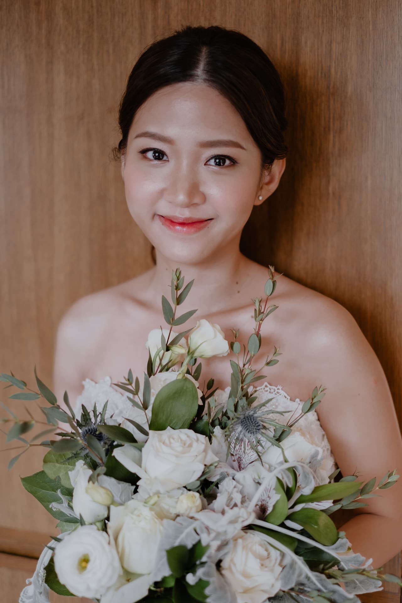 Bride with a sleek low bun, holding her white and green bouquet