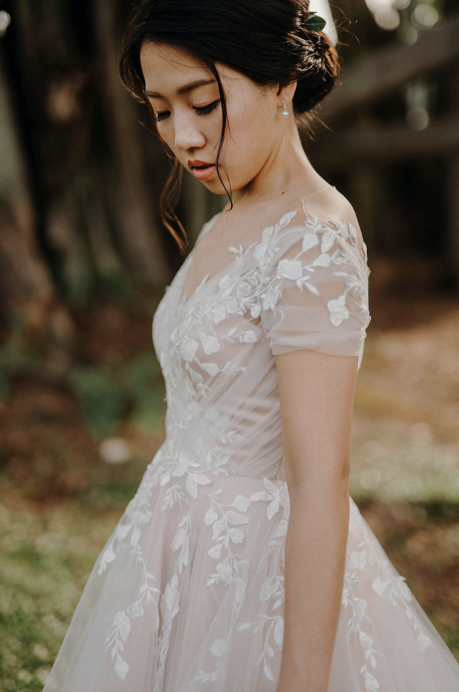 Bride in her floral lace gown in the garden, eyes lowered