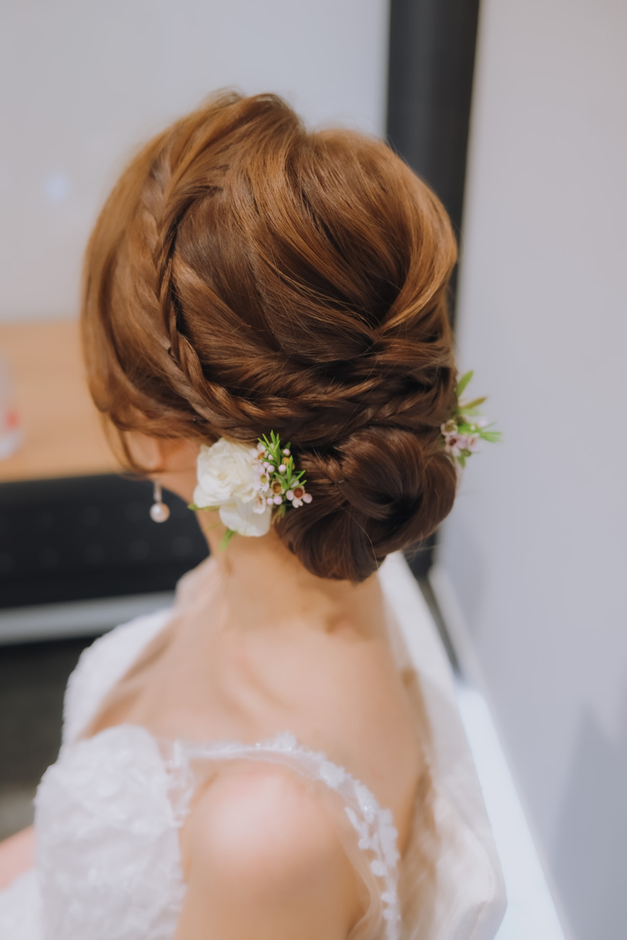 Bride's braided updo with a white rose and baby's breath