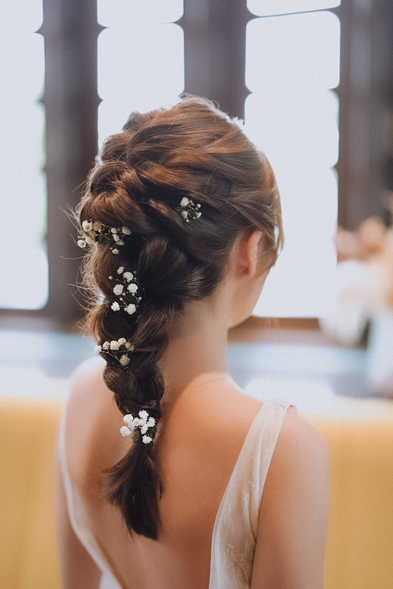 Bride's braided low ponytail scattered with baby's breath