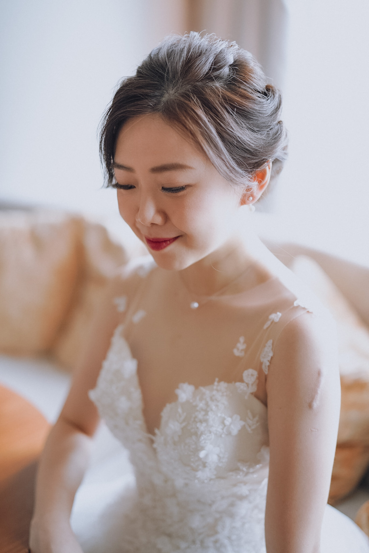 Bride fastening her earring in her off-shoulder lace gown
