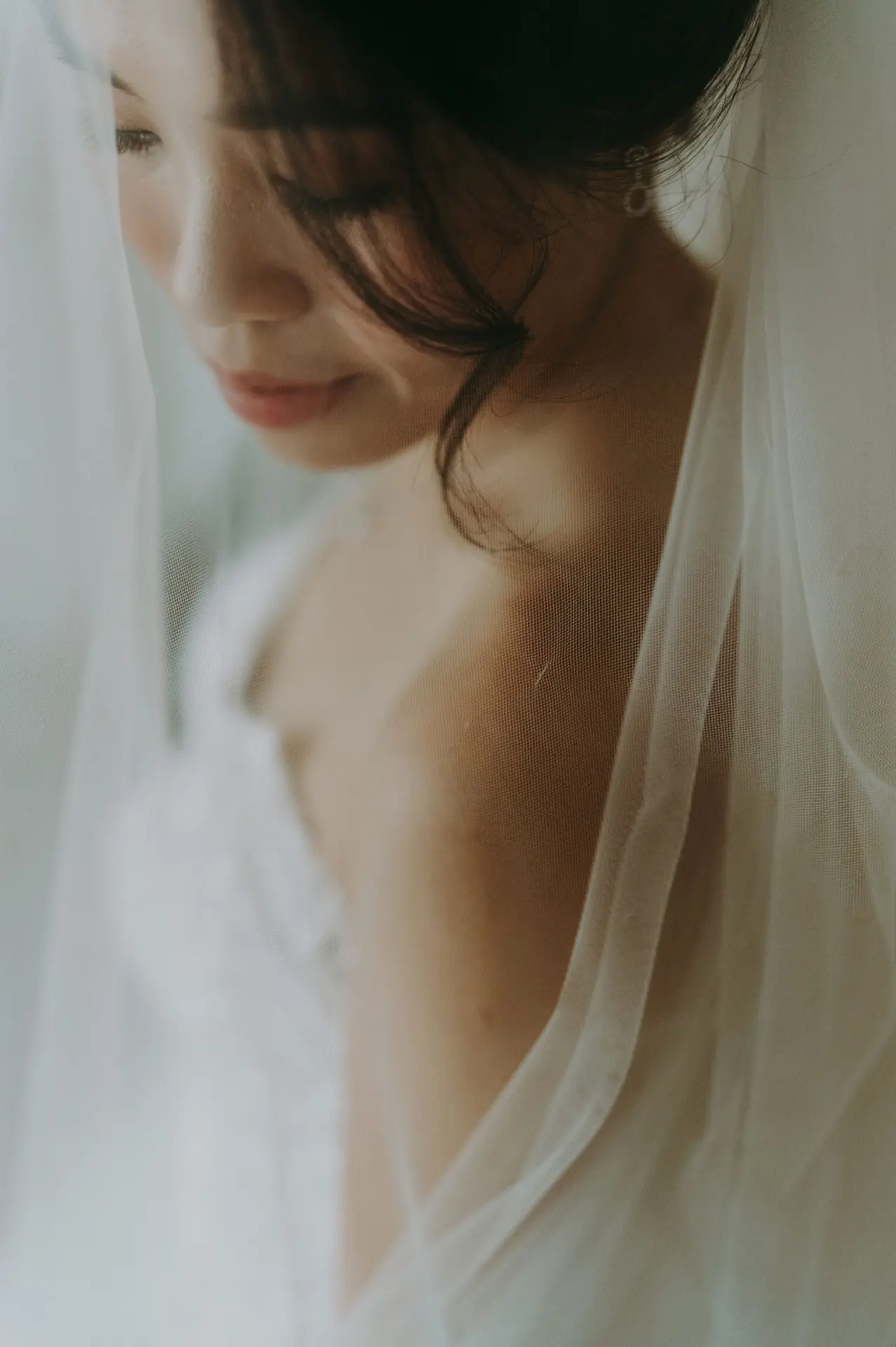 Bride — soft portrait through the veil, eyes lowered
