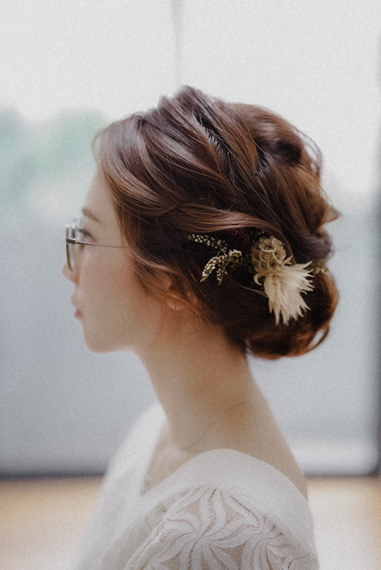 Bride in profile, updo with dried flowers and glasses